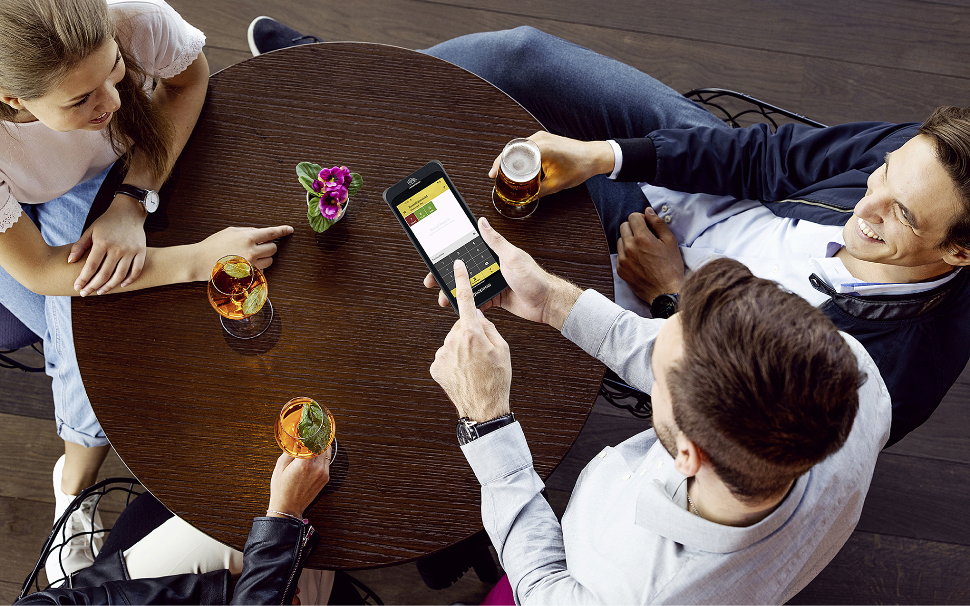 4 Personen sitzen an einem Restauranttisch und bestellen über ein Smartphone